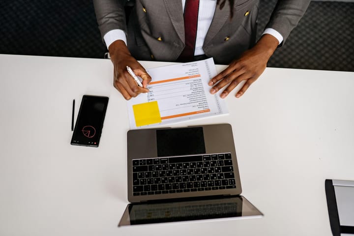 Top view of a business professional analyzing documents with a laptop on a white desk in an office setting
